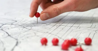 eine Hand steckt einen Pin in eine Karte