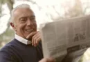 älterer Mann liest Zeitung und lächelt