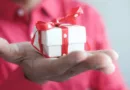 Männerhand mit einem kleinen weißen Geschenk mit roter Schleife