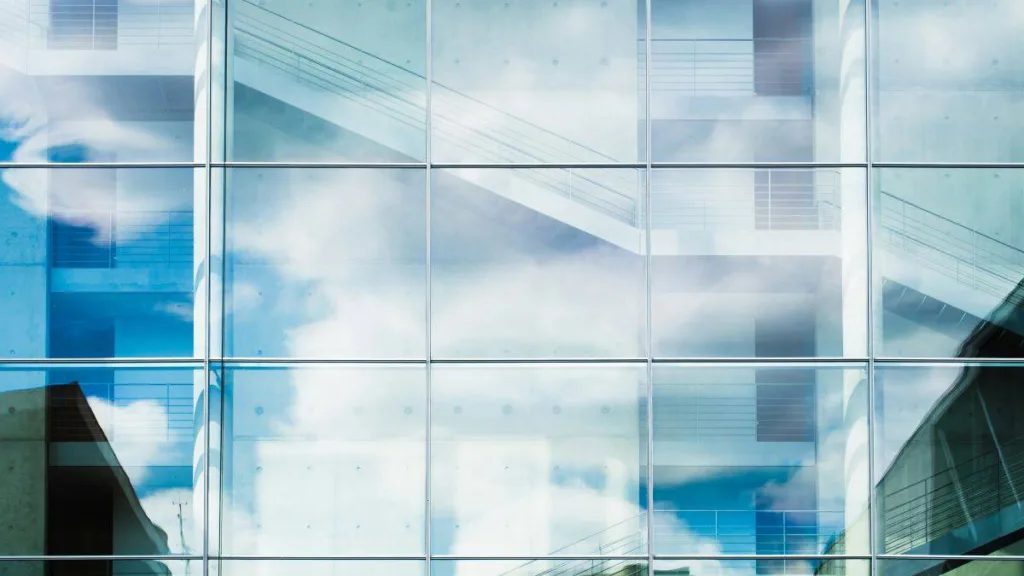 Ansicht einer reflektierenden Glasfassade mit Wolken
