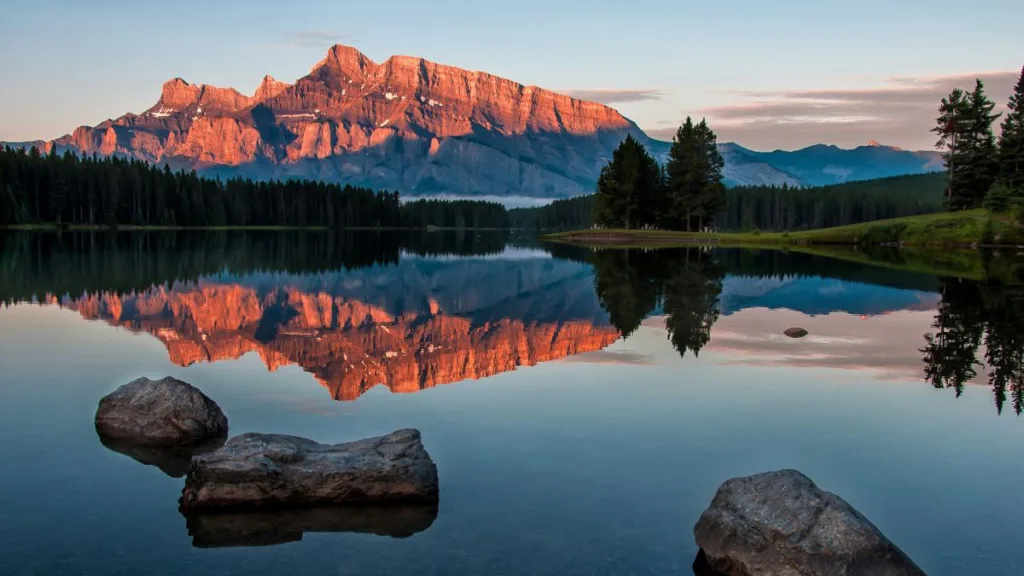 ein großer roter Berg spiegelt sich in einem See während der Dämmerung