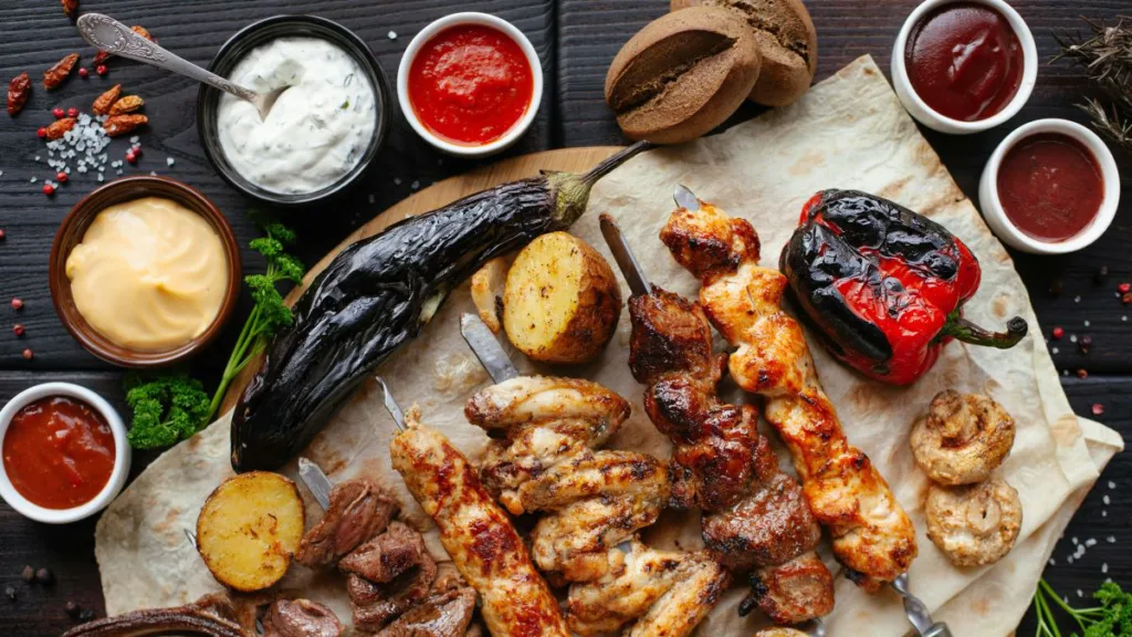 verschiedenes Grillgut und verschiedene Soßen auf einem Tisch