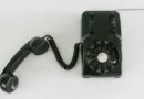 Ein altes schwarzes Telefon mit abgenommenen Hörer liegt auf einem Tisch