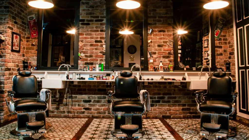 Barbershop mit drei klassischen Bedienplätzen, Spiegeln, Arbeitsleuchten und Friseurausstattung vor gemauerter Wand