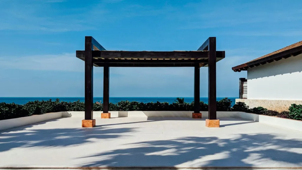 eine Pergola aus Holz auf einer Terrasse mit Meerblick
