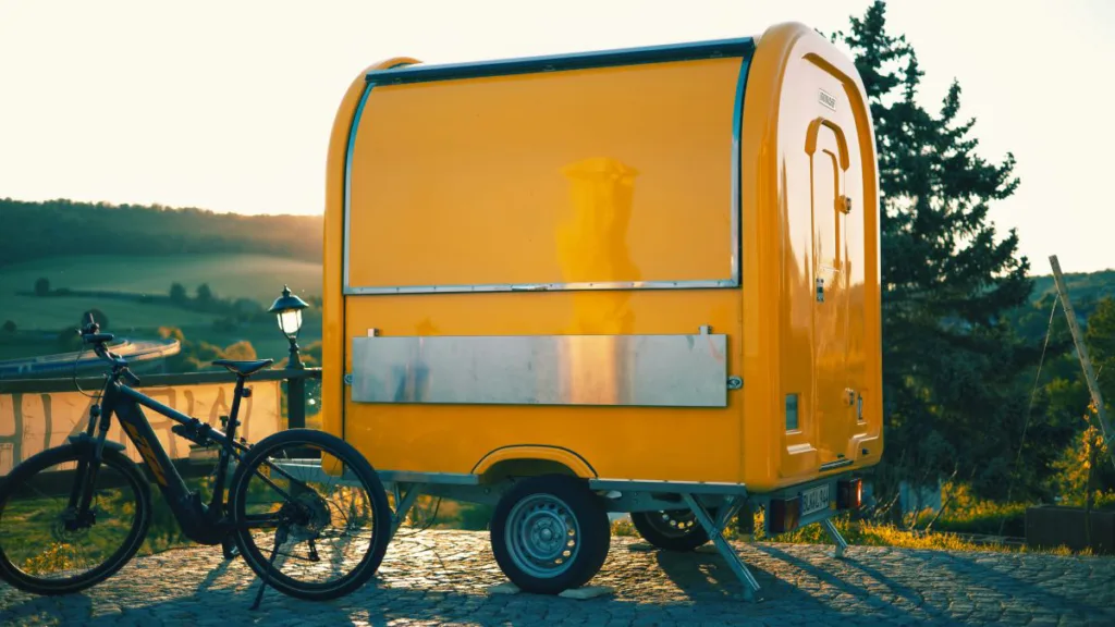 ein gelber Anhänger und ein E-Bike mit grüner Landschaft im Hintergrund