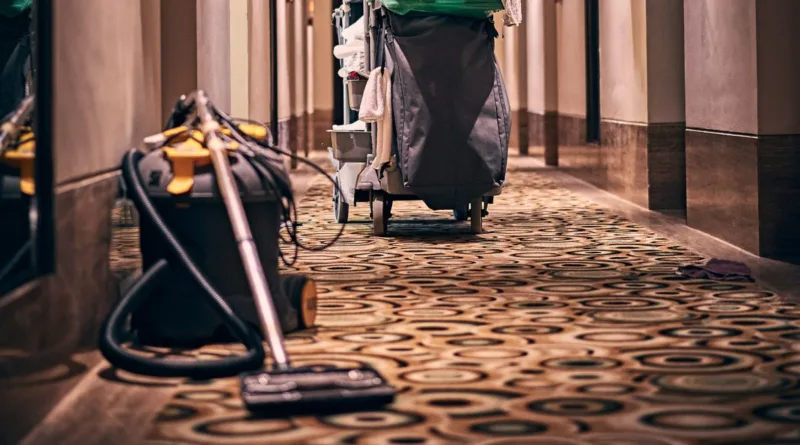 ein älterer Hotelflur mit einem Reinigungswagen und einem Staubsauger
