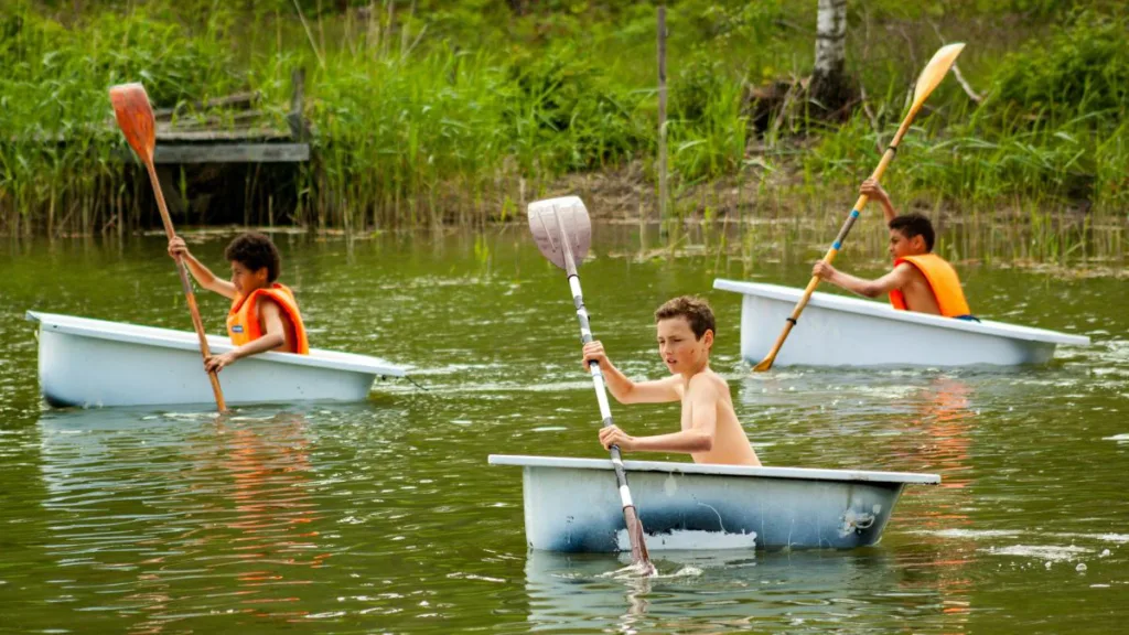 3 Kinder paddeln auf einem See in jeweils einer Badewanne