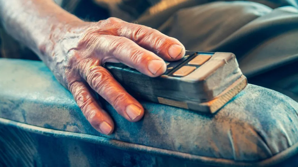 ältere Hand benutzt eine alte Fernbedienung
