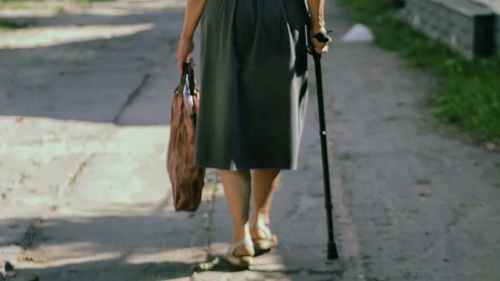 Frau mit Gehstock von hinten