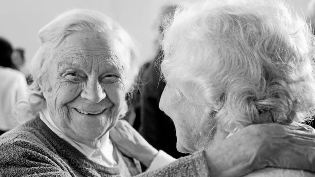 zwei ältere Frauen tanzen und lachen, Bild ist in schwarz/weiß gehalten
