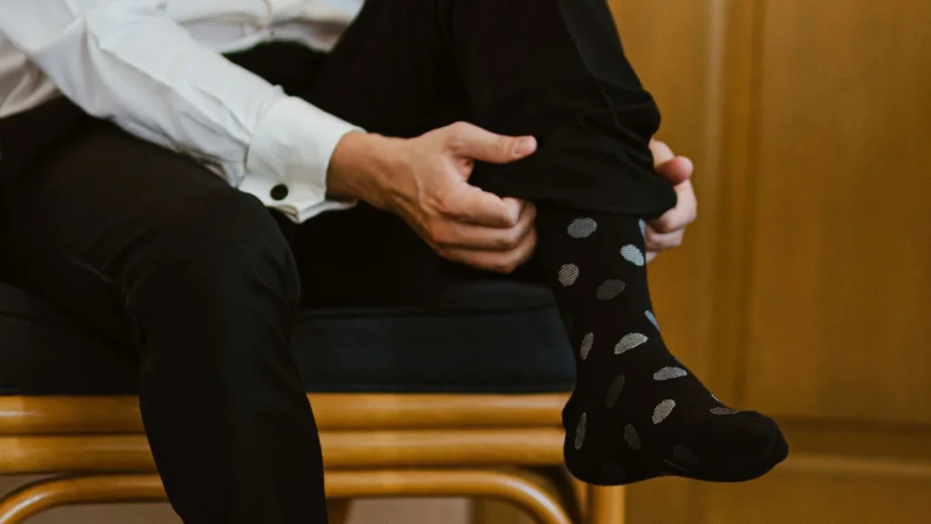 ein Mann zieht sich eine Socke hoch