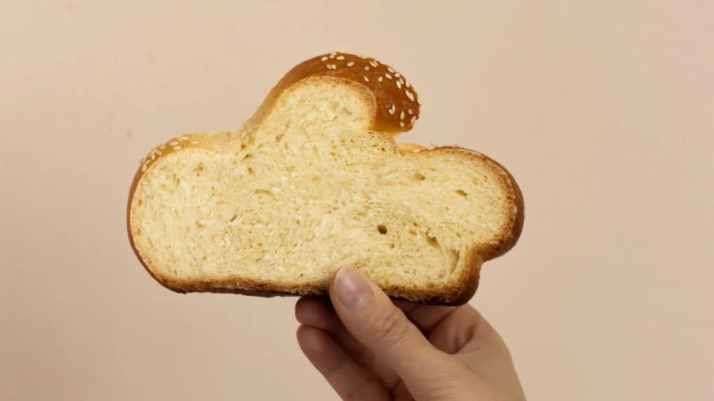 eine Hand hält eine Scheibe Weißbrot hoch, die aussieht, wie eine Wolke