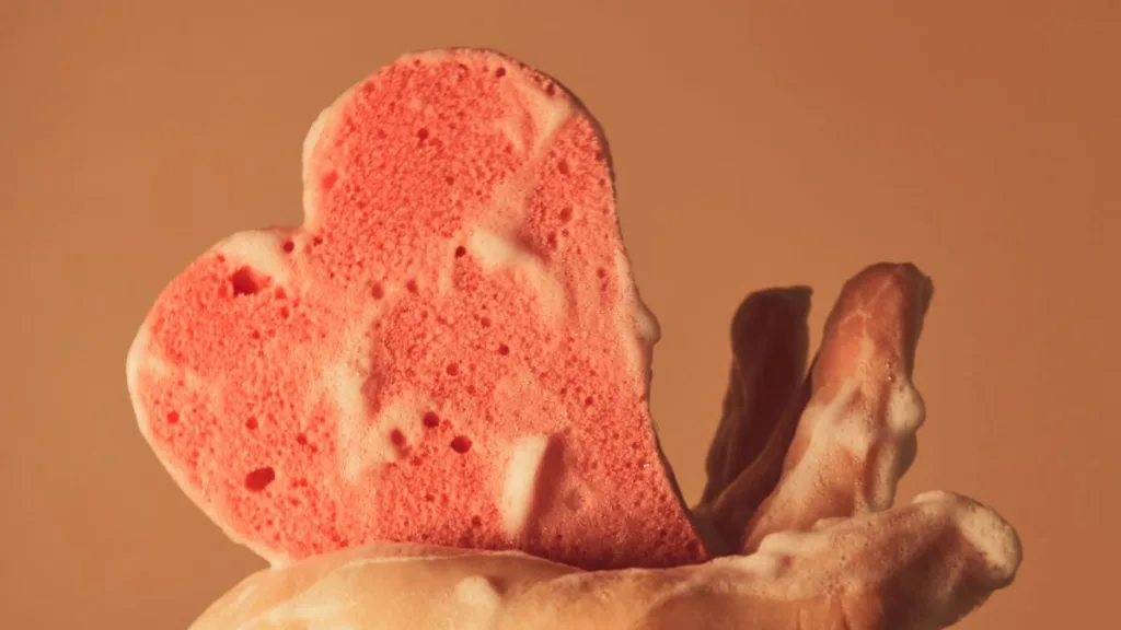 ein Schwammherz liegt auf einer Hand mit viel Schaum