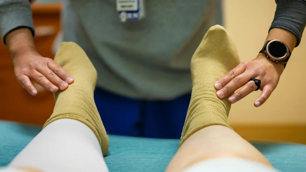 zwei Hände massieren zwei Füße mit Socken