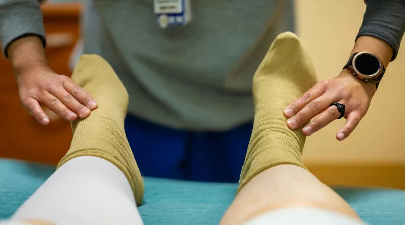 zwei Hände massieren zwei Füße mit Socken