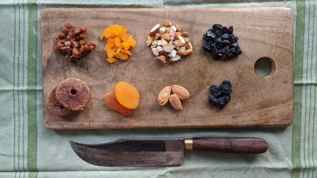 vorzerkleinerte Zutaten liegen auf einem Holzbrett mit einem Messer drunter