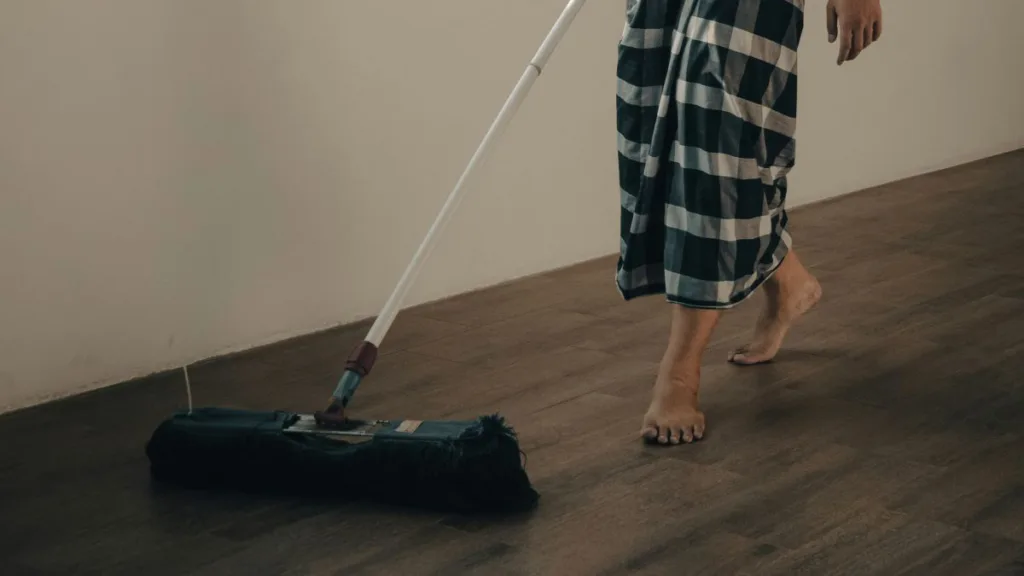 ein Mann reinigt mit einem normalen Wischmop den Fußboden