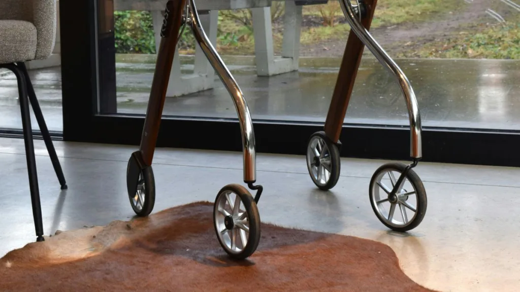 die vier Räder von einem Leichtgewicht-Rollator vor einem Fenster