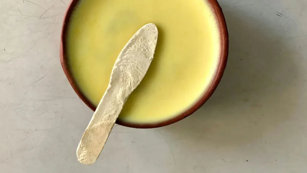 ein feines gelbes Mus in einer Schüssel und ein Holzlöffel drauf