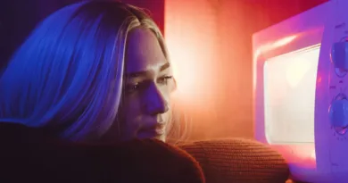 eine blonde Frau schaut in eine leuchtende Mikrowelle