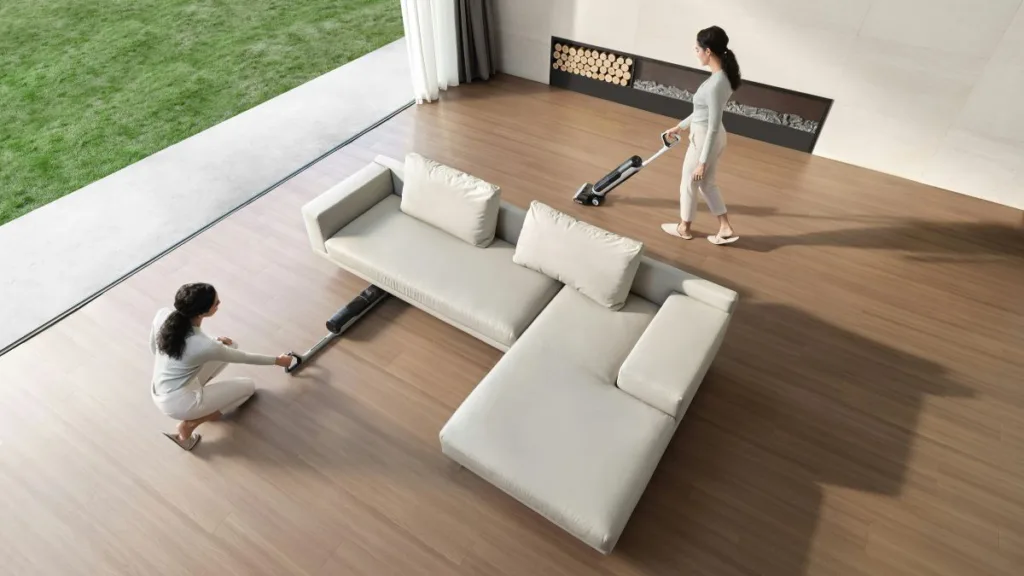 eine Frau saugt mit einem Nass-Trockensauger um eine Couch herum