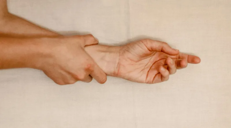 eine rechte Hand hält den Arm Höhe Handgelenk der linken Hand