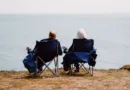 zwei Rentner sitzen in Klappstühlen und schauen aufs Meer