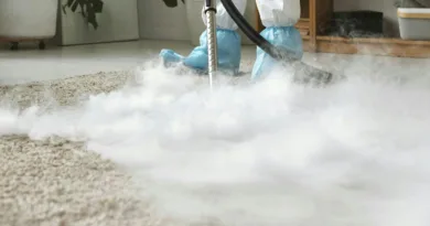 ein Mann in Schutzanzug säubert mit viel Dampf einen Teppich