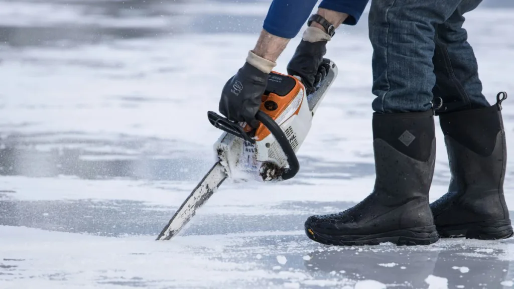 ein Mann sägt in eine Eisfläche mit einer Kettensäge