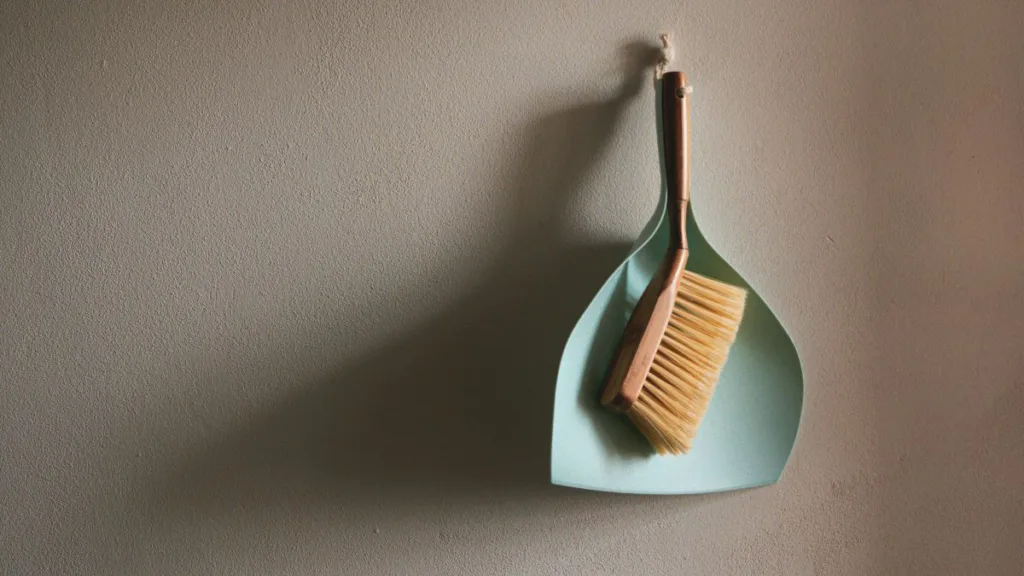 ein Handfeger und eine Kehrschaufel hängen an der Wand