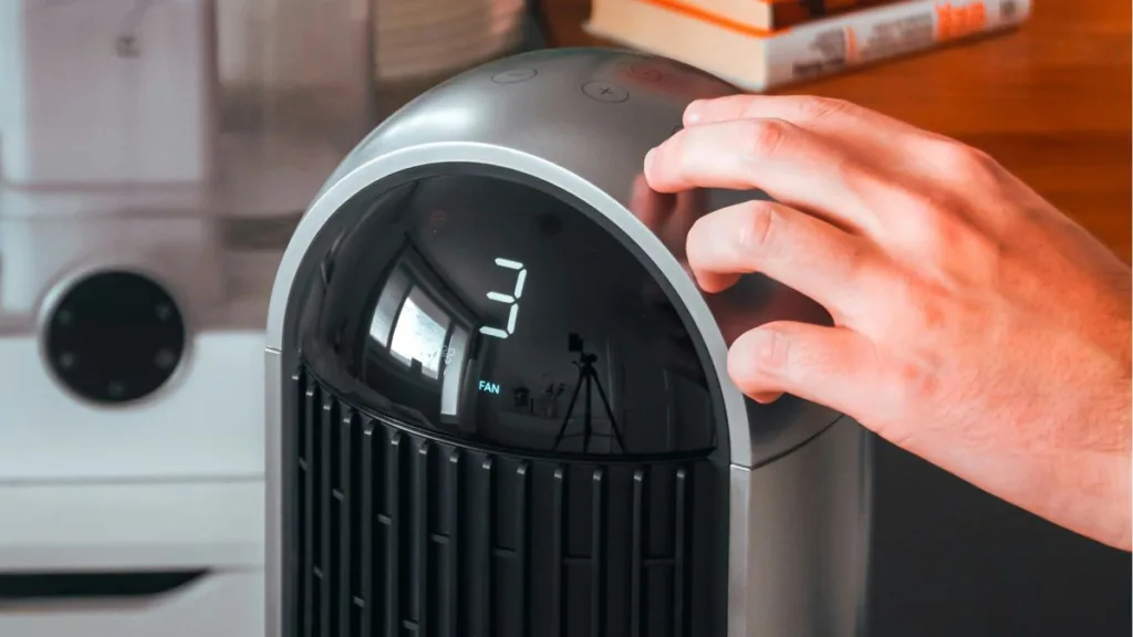 eine Hand stellt an einen Luftreiniger die FAN-Geschwindigkeit ein