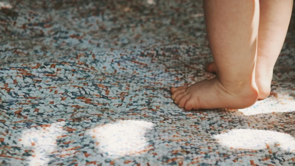 zwei Babyfüße laufen auf einen Teppich