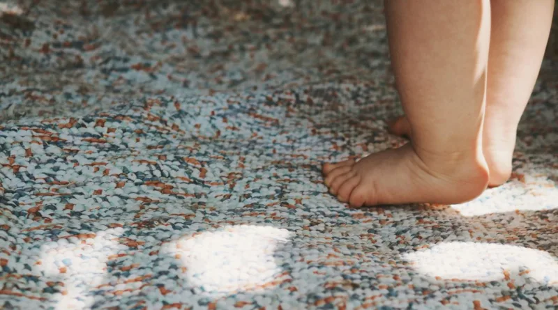 zwei Babyfüße laufen auf einen Teppich