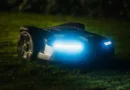 ein Rasenmähroboter in der Nacht mit Scheinwerfern