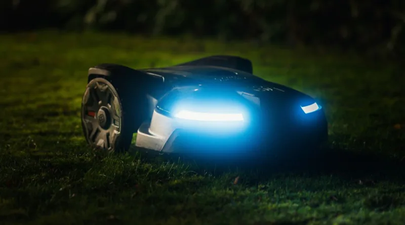 ein Rasenmähroboter in der Nacht mit Scheinwerfern