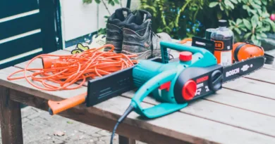 eine Elektro-Kettensäge und diverses Arbeitszubehör liegen auf einem Tisch