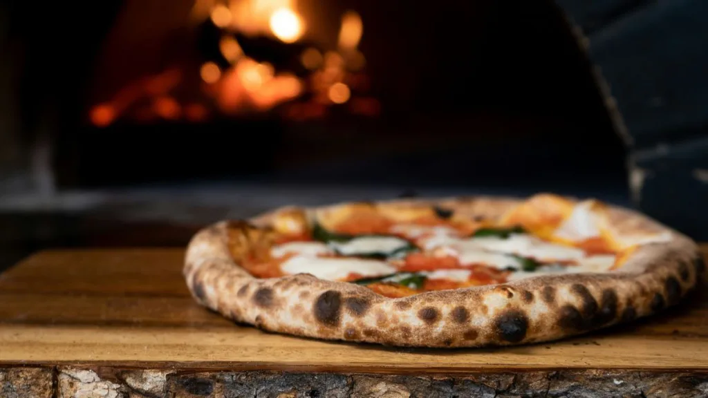 eine knusprige Pizza vor einem Holzofen