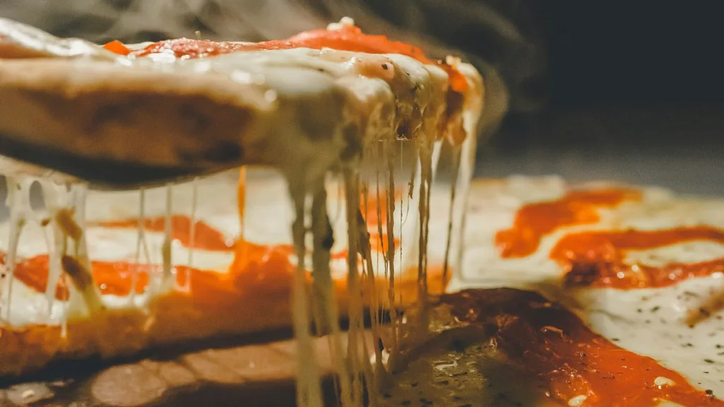 zerlaufender Käse einer Pizza beim anheben eines Stückes