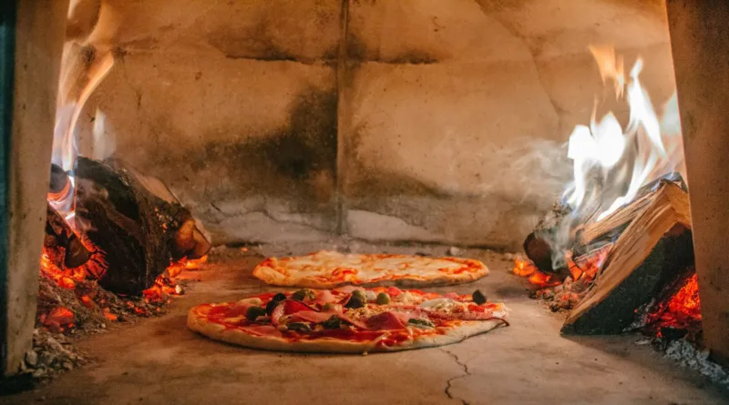 zwei Pizzen garen gerade in einem Holzofen