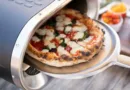 eine Pizza wird mit einem Pizzaschieber in einen elektrischen Pizzaofen geschoben