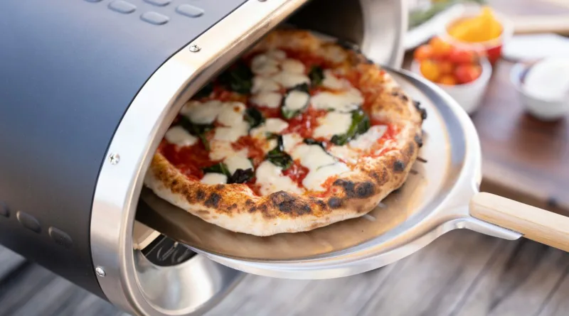 eine Pizza wird mit einem Pizzaschieber in einen elektrischen Pizzaofen geschoben