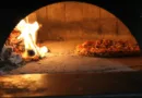 Ansicht in ein Holzkohleofen, liks das Feuer und rechts eine Pizza