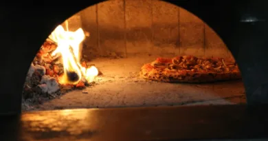 Ansicht in ein Holzkohleofen, liks das Feuer und rechts eine Pizza
