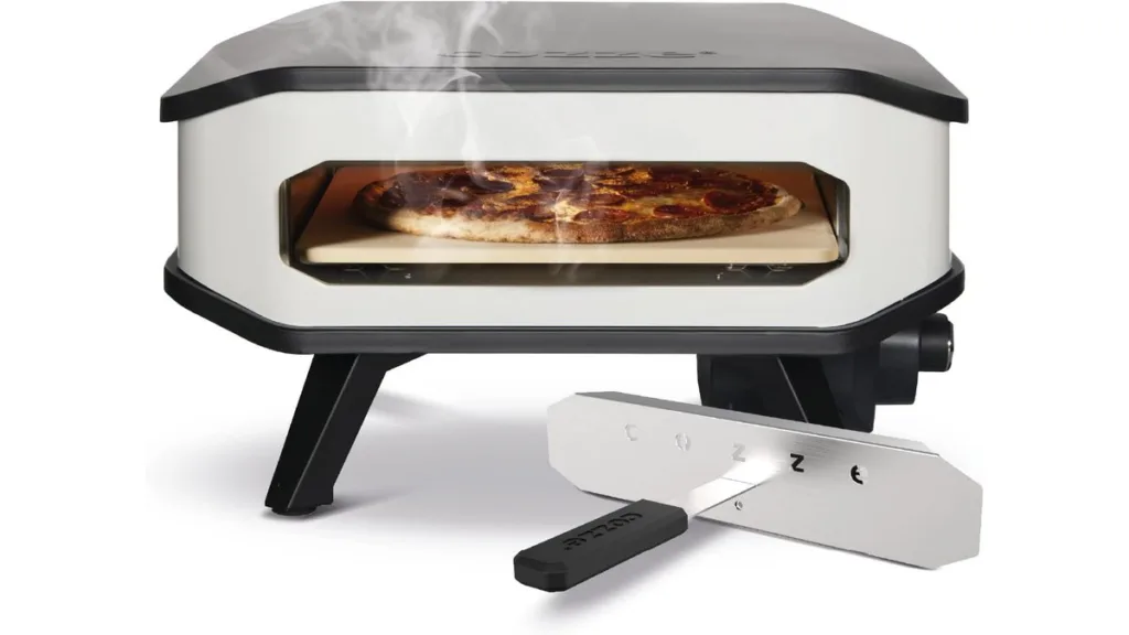 Cozze 13 Zoll Elektro-Pizzaofen mit einer Pizza auf dem Backstein und dem dazugehörigen Hitzeschild im Vordergrund