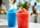Rote und blaue Slushgetränke in durchsichtigen Bechern auf hellem Tresen