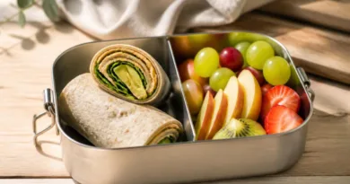 Stilvolle Lunchbox mit Sandwich und Obst auf Holztisch