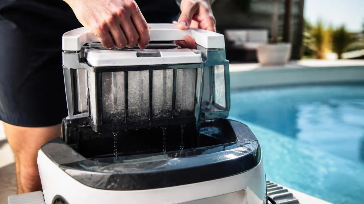 Person entnimmt Filterkorb aus Poolroboter